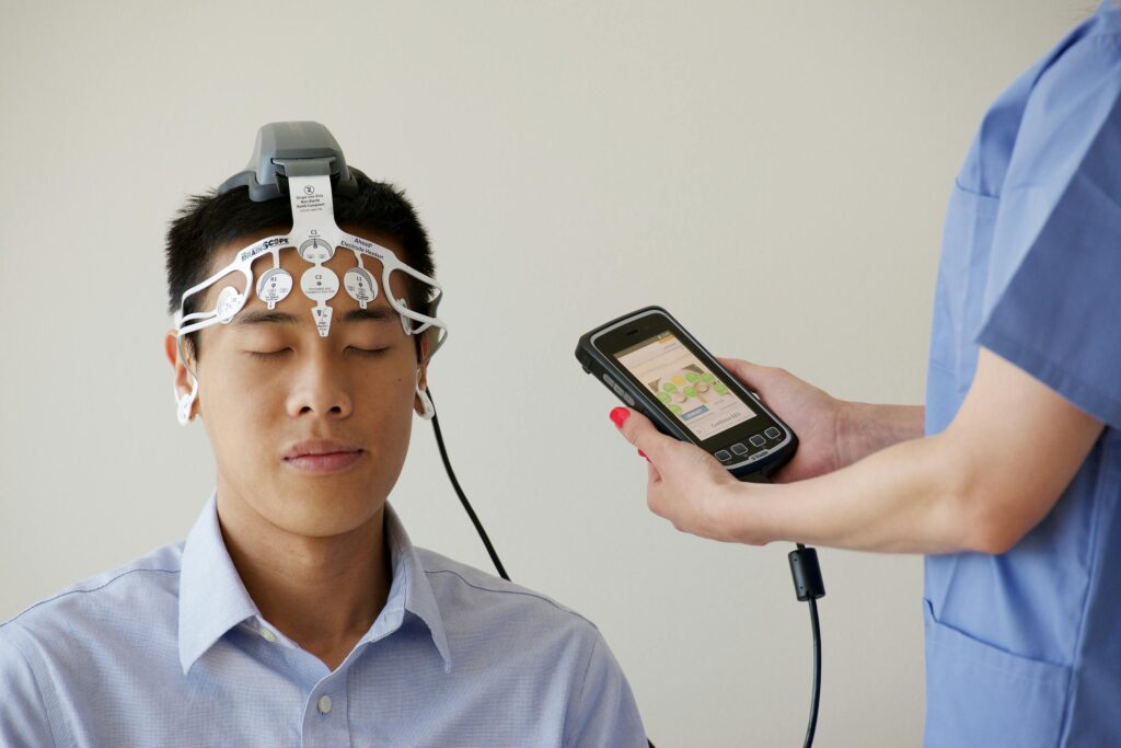 Healthcare professional conducting an EEG examination using a Brainscope device on a male patient.