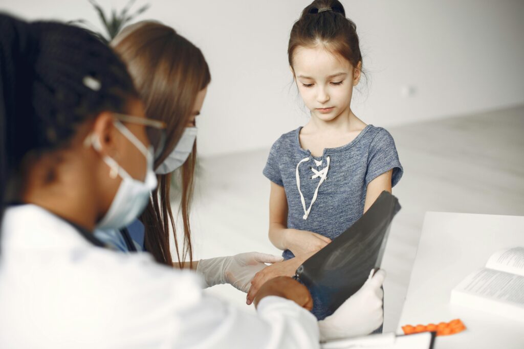 Young girl undergoing a medical checkup with doctors reviewing her x-ray